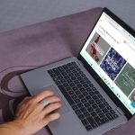 Yoga international website open in browser on a laptop, set on a yoga mat, with a hand selecting the course.
