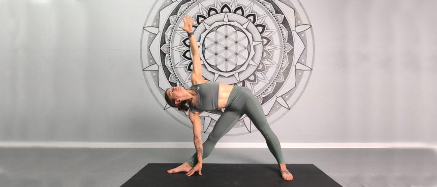 Extended Triangle Pose (Utthita Trikonasana) demonstrated by a flexible and experience female yoga teacher.