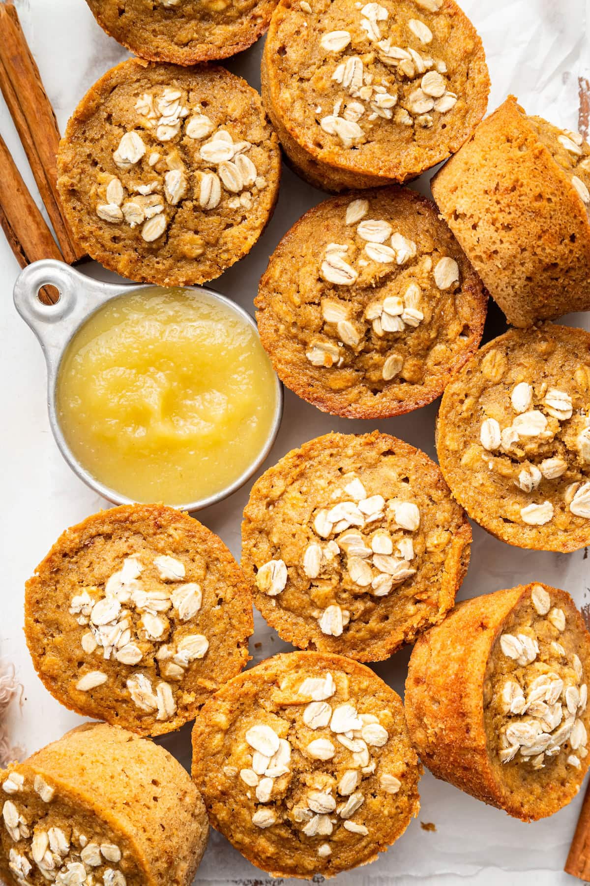 Baked applesauce muffins arranged with a small bowl of applesauce