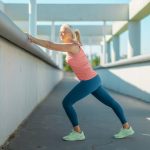 mature woman outside doing wall calf stretch
