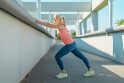 mature woman outside doing wall calf stretch
