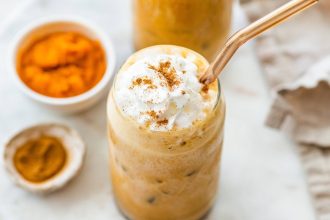 Iced pumpkin spice latte topped with whipped cream and a sprinkle of cinnamon.