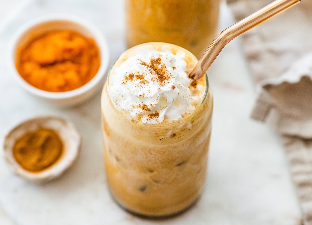 Iced pumpkin spice latte topped with whipped cream and a sprinkle of cinnamon.