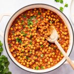 Thick and flavorful chana masala simmering on the stovetop with a wooden spoon.