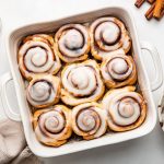 Protein cinnamon rolls in a square baking dish topped with an icing.