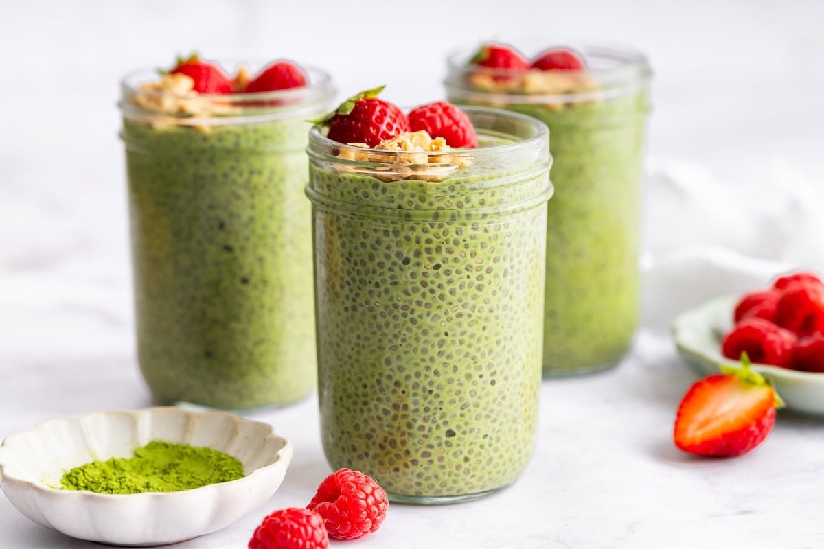 Matcha chia pudding in glass jars with strawberries and crunchy toppings for meal prep.