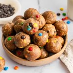 Bowl of monster cookie protein balls made with oats, peanut butter, chocolate chips, and M&M’s.
