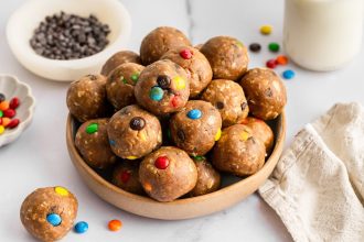 Bowl of monster cookie protein balls made with oats, peanut butter, chocolate chips, and M&M’s.
